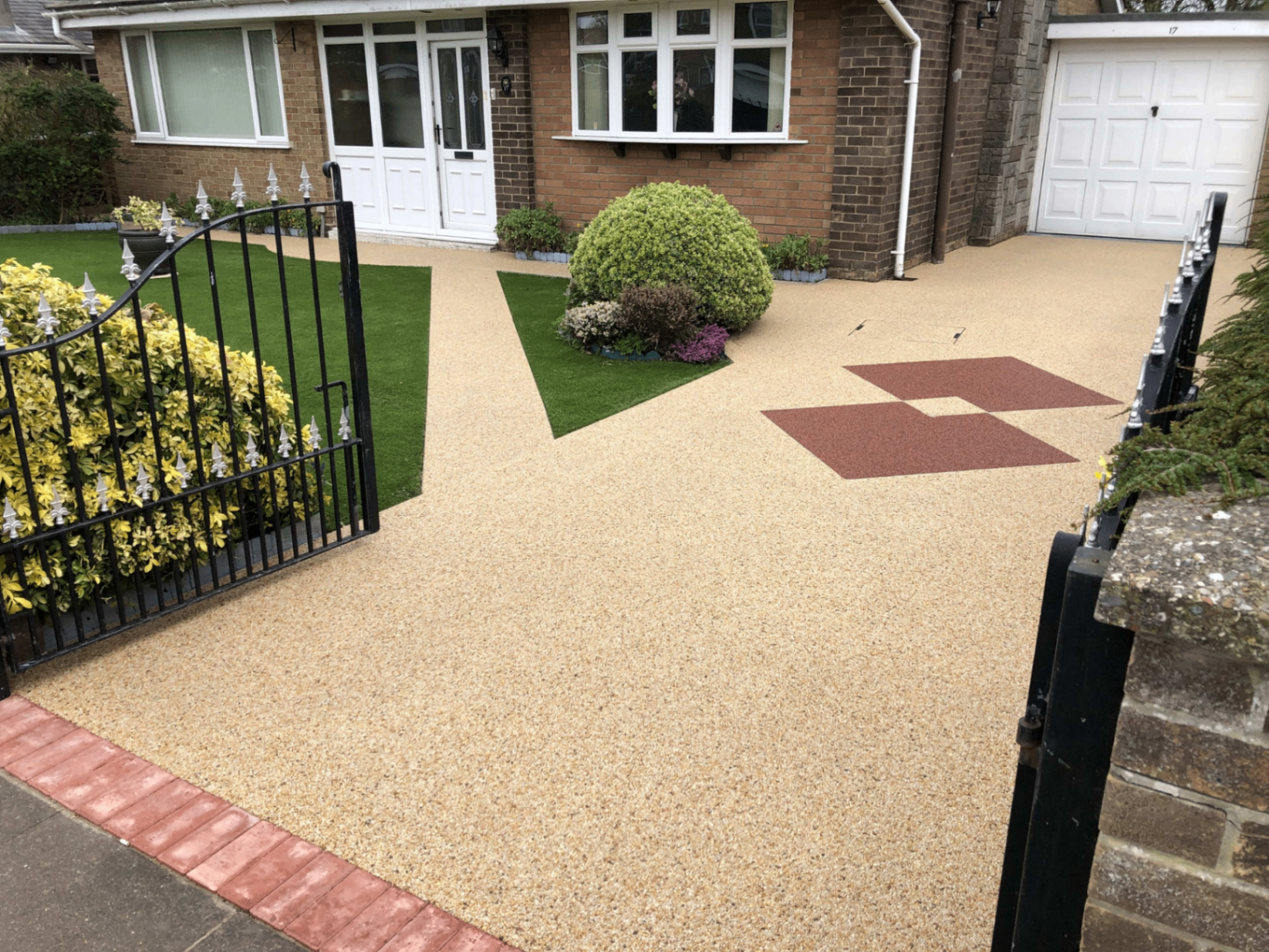 Resin bound driveway in a natural gold aggregate with red feature squares, leading to a UK home